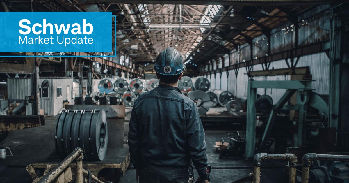 Schwab Market Update: Photograph depicts a rear view of a worker standing alone and looking out upon a factory floor. 