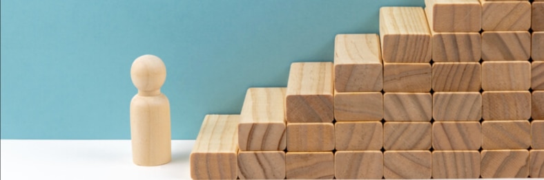 A wooden figure standing in front of a staircase made of wooden blocks.